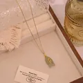 Makro-Detail des Fisch-Natursteinanhängers mit rosa Edelsteinen und Goldkette - Grüner Aventurin