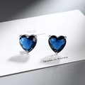 Macro shot of heart-shaped earrings with deep blue zircons set in silver claws - Royal Blue Zirconia