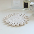 Detail of a round woven cotton rope coaster in off-white on a light surface - 18cm / Off-white