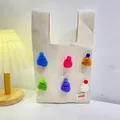 Beige knitted tote bag with colorful mini hat accents and brand label on a desk - Colorful Hat Beige