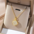 Detailed close-up of a golden square pendant with micro-pave crystals in a luxury beige box - Choker Necklace / Gold