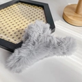 Large light grey faux fur hair claw clip for thick hair shown in a cozy setting - Gray