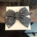 Detail view of a large black bow hair clip featuring sparkling rhinestones in a gift box - Navy Blue Rhinestone