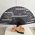 Black Chinese folding fan with bamboo and dragonfly print on a wooden stand - Bamboo Smoke and Moon