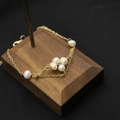 Elegant gold pearl bracelet with floral cluster beads on dark walnut wood stand - Rhombus Small Flower Bracelet