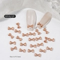 Close-up of 6.5x3.5mm rose gold mini bow nail charms for professional manicures - Pearlescent Champagne
