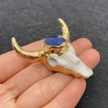 White bull head pendant with gold horns and blue stone held in hand for size - No. 4 - Light Blue Stone
