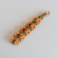 Detail of handmade woven sunflower keychain with yellow petals and gold metal ring - Yellow