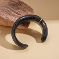 Macro detail of black marble texture resin cuff bracelet on natural stone background - Black