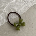 Elegant green acrylic bow hair tie with dark brown elastic band on a textured surface - Green