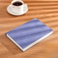 Blue A5 faux leather notebook with embossed text on a wooden desk with coffee cup - Ruled / A5-Sky Blue