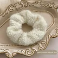 Close-up of white plush scrunchie with 5cm inner diameter on vintage ceramic tray - Curly Faux Fur