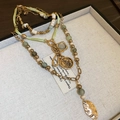 Dettaglio della collana bohémien a strati con moneta a farfalla e ciondoli a foglia testurizzati - Stile Farfalla Oro-Verde