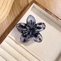 Detail of a dark blue marble resin flower hair claw on a wooden jewelry display - Grey Leopard