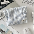 Dettaglio della borsa trucco a scacchi blu con fiocco ricamato su una scrivania pulita - Griglia Blu Fiocco Blu