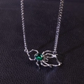Collana con pendente a ragno d'argento e gemma verde su sfondo di pelle nera - Collana con Ragno Verde
