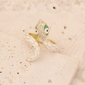 Macro shot of gold snake ring with white enamel scales and shimmering zircon accents - White