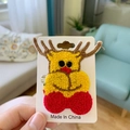 Handgefertigte gehäkelte Weihnachts-Rentier-Haarspange auf weißer Karte mit Strickdetails - Elch