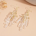 Detalle de elegantes pendientes dorados de borla con colgantes de cristal claro - Gancho de oreja - Borla de gota de agua