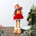 Detail of gingerbread man doll with red dress and candy cane standing near a Christmas tree - Gingerbread Man Stretchable Doll Female