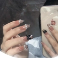 Close-up of black and nude French nails with rhinestones and black bows on hands - Z502 French-style Black-edged Chain / Nail Glue Version