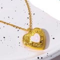 Goldene Herz-Medaillon-Halskette mit opalisierendem Stein auf weißem Keramikteller - Weiß