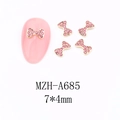 Macro detail of 7x4mm rose pink bow nail charms with gold base and rhinestones - A685