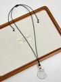 Detail of silver flower pendant on black wax cord with wood bead accent on beige linen - Silver C-Shape with Beads