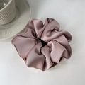 Macro shot of elegant dusty pink satin scrunchie with silky texture on white surface - Pink
