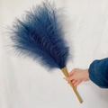 Hand holding dark blue artificial pampas grass bouquet with wooden stems on white fabric - 53-55cm / Dark Blue