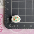 Macro shot of a mini cat resin dessert charm with floral pattern on a scale mat - White Bear Bowl Vegetable Soup