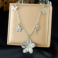 Silver flower and butterfly pendant necklace on a beige display stand for women - Silver Style (N3712)