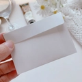 Single white minimalist paper envelope for cards held in hand with a floral background - White Envelope