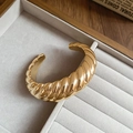 Detailansicht eines goldfarbenen Croissant-Armreifs in einer Schmuckschatulle - Armreif-Gold-Gerippt