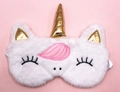 Detail of plush white unicorn sleep mask with golden horn and pink mane on pink background - White Gold Horn