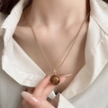 Macro detail of gold-plated necklace featuring a tiger eye stone pendant on a twisted chain - 33# Necklace-Gold-Coffee