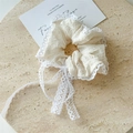 Detailansicht eines weißen Seersucker-Haargummis mit Spitzenbesatz und langer Schleife - Spitzenkante Scrunchie / Beige