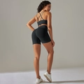 Detail view of seamless black yoga set with cross-back sports bra and high-waisted shorts - S / Black