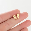 Close-up of golden leaf stud earrings with detailed veins held by fingers on white background - Leaf / Gold