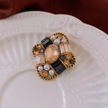 Detalle macro del broche vintage con piedra champán, perlas y cristales - Dorado