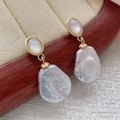 Close-up of Baroque pearl earrings with golden shell inlay on a jewelry display - White Shell