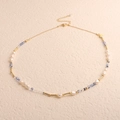 Detailed view of baroque pearls with blue beads and golden accents on a cream background - Irregular Baroque Floral Blue Crystal
