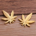 Primer plano macro de dos colgantes de metal con forma de hoja de arce dorada en madera - 22x25mm / Oro Pequeño