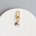 Detail of calico cat enamel charm with gold lobster clasp on white ceramic plate - Calico Cat