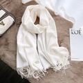 Cream white faux cashmere scarf with fringe details laid on a soft plush background - Cream