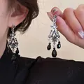 Dettaglio di orecchini retrò in argento con perle nere e motivi traforati in stile etnico - Stile Nappa Retrò con Perla Nera a Goccia