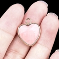 Ciondolo a cuore in pietra naturale rosa con bordo dorato tenuto sulle dita - Quarzo Rosa Bordo Dorato