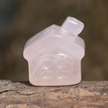 Macro shot of a pink rose quartz house carving placed on a rustic wood surface - Rose Quartz