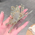 Golden butterfly hair claw clip with sparkling rhinestones held against a cafe background - Gold Rhinestone Bamboo Butterfly