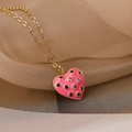 Detalle macro del colgante de corazón dorado con esmalte rosa y circonitas de colores - Rosa
